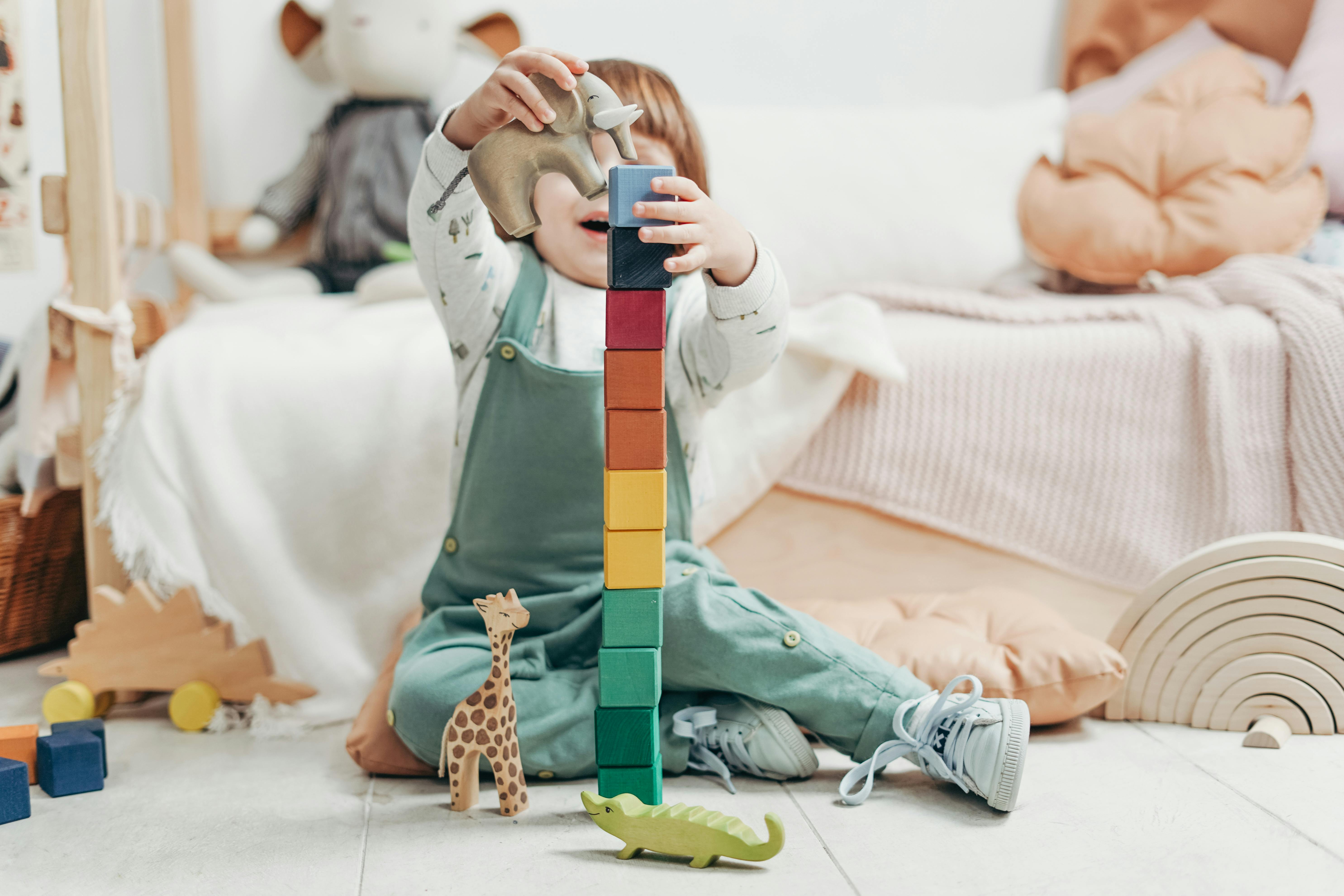 Child doing imaginative play with animals and stacking blocks.