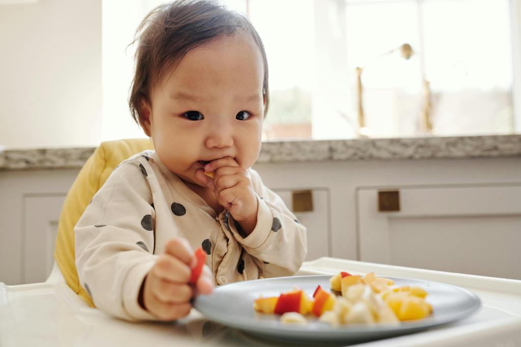 baby feeding themselves solid food