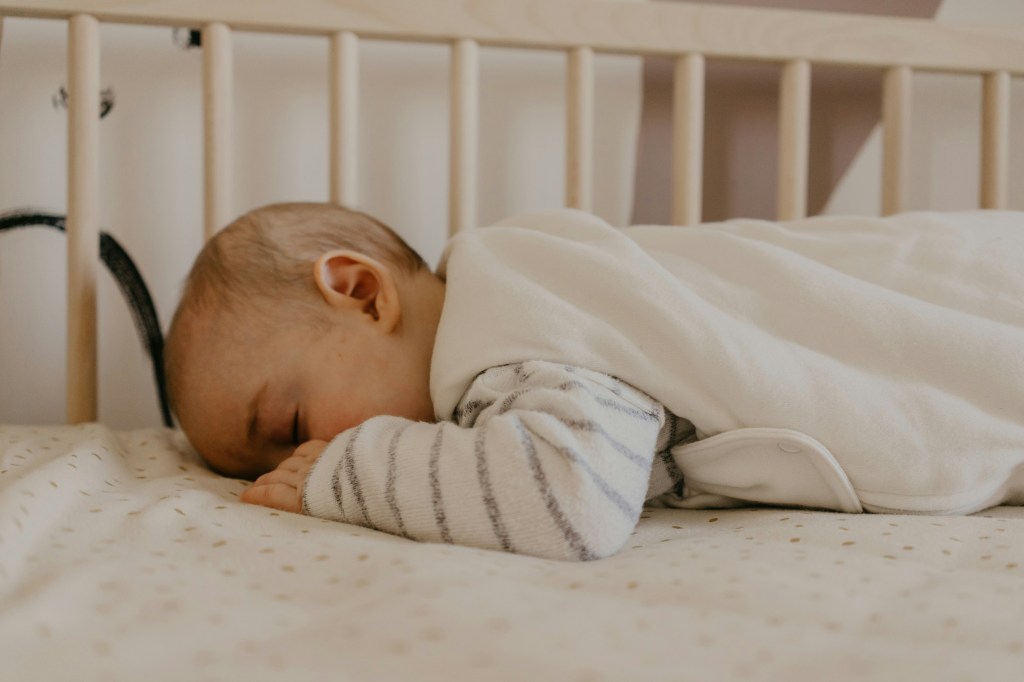 baby sleeping in their crib in a sleep sack