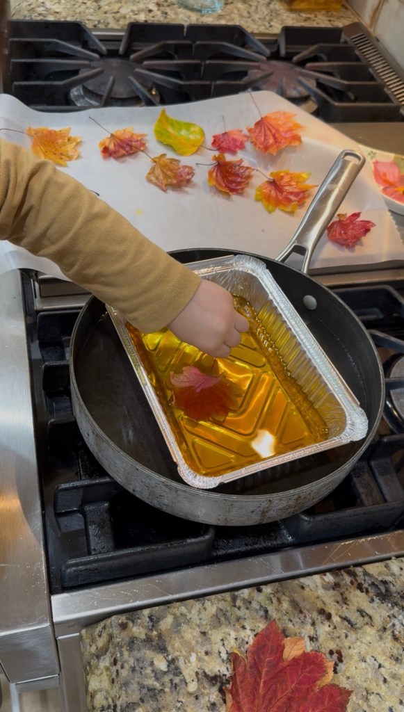 child dipping leaves in beeswax